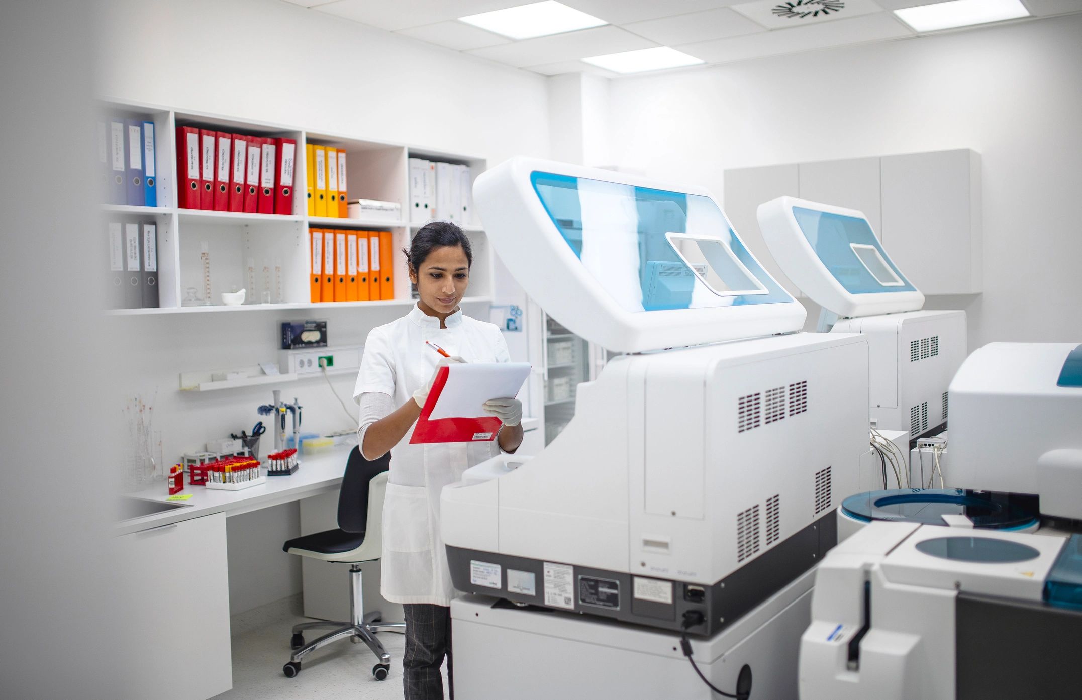 Medical researcher in a lab reviewing data beside diagnostic equipment